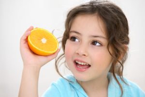 Criança segurando uma laranja para comer